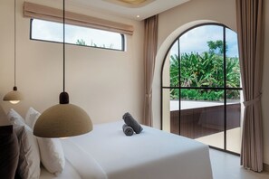 A bedroom with a large bed, two pendant lights, a view of greenery through a window, and a view of the sky through another window. - Kamala Villa by Betterplace (Pecatu)