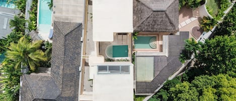 A residential property with a swimming pool, a covered patio, and lush greenery.