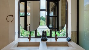 A bathroom with a large mirror, two sinks, and a view of greenery outside. - Kamala Villa by Betterplace (Pecatu)