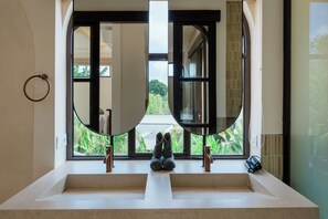 A bathroom with a large mirror, two sinks, and a view of greenery outside. - Kamala Villa by Betterplace (Pecatu)