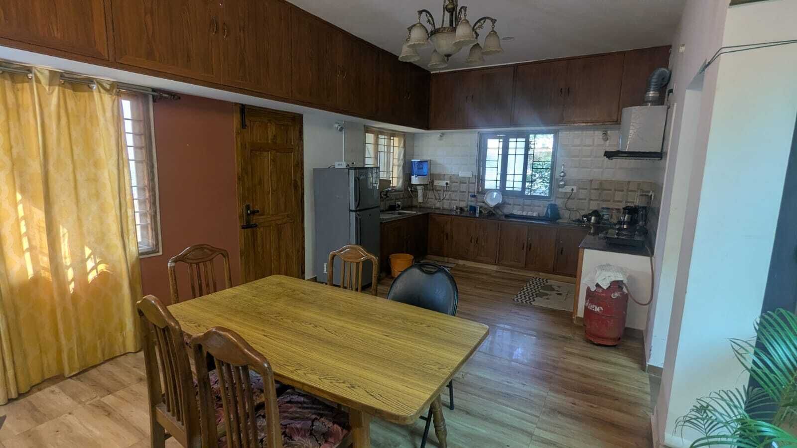 Una cocina compacta con armarios de madera, una mesa de comedor con sillas y un refrigerador.