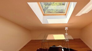 A room with a skylight, a table, and a chair. - Le Belvédère de La Montille (sleeps 6) (Mont-Dore)