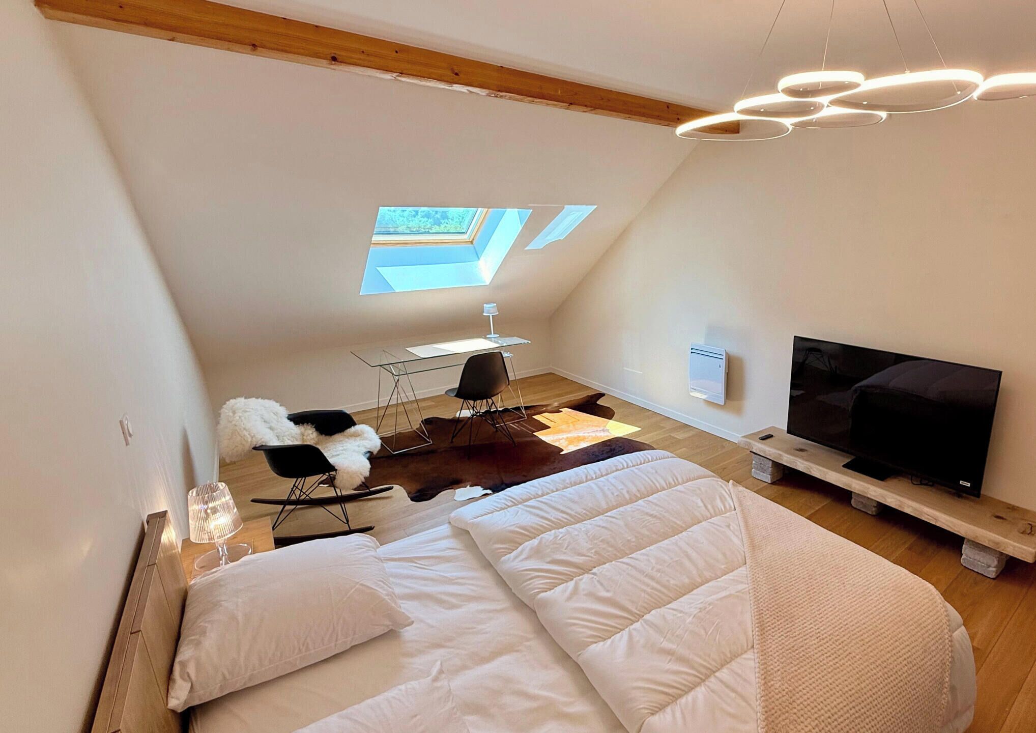 Une chambre de style loft moderne, dotée d’un grand lit, d’une télévision, d’un bureau et d’une chaise.