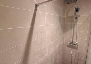Ein Duschbereich mit Handbrause und einer fest installierten Bedienkonsole.