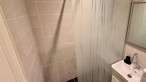 A bathroom with a shower, a sink, and a mirror. - Fenestre La Bourboule Park (4 people) (La Bourboule)