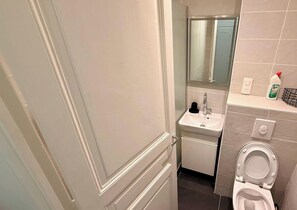 Et badeværelse med toilet, vask og spejl.