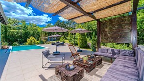 Eine Außenpatio mit Pool, Liegestühlen, einer Couch und Holztischen.