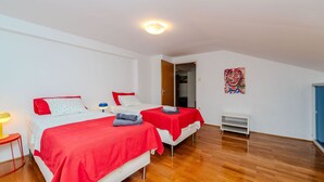 A room with two beds, a wooden floor, a painting on the wall, and a door leading to another room. - Villa Sandra by Villas Guide (Veli Brgud)