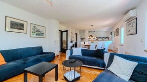 A modern living room with a sofa, a coffee table, and a dining area in the background. - Villa Sandra by Villas Guide (Veli Brgud)