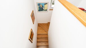 A staircase with wooden steps leading upwards, flanked by white walls and framed artwork. - Villa Sandra by Villas Guide (Veli Brgud)