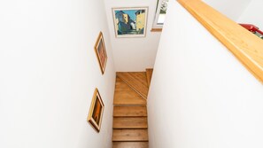 Eine Treppe mit Holzwegen, die nach oben führt, gesäumt von weißen Wänden und umrahmt von Kunstwerken.