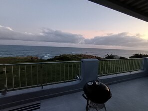 Uma varanda com vista para o oceano, churrasqueira e grade.