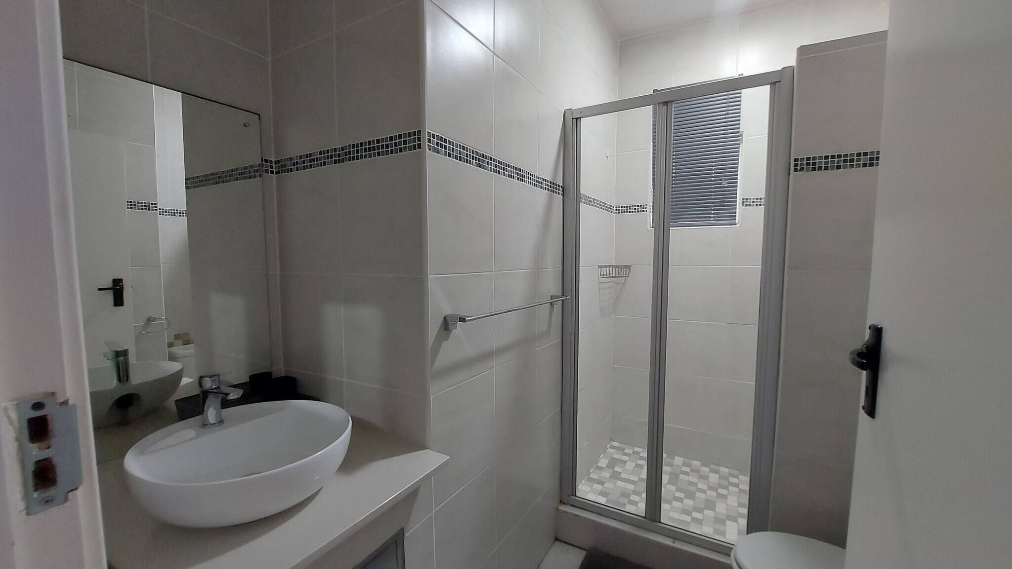 A bathroom with a white sink, a mirror, and a glass-enclosed shower area.