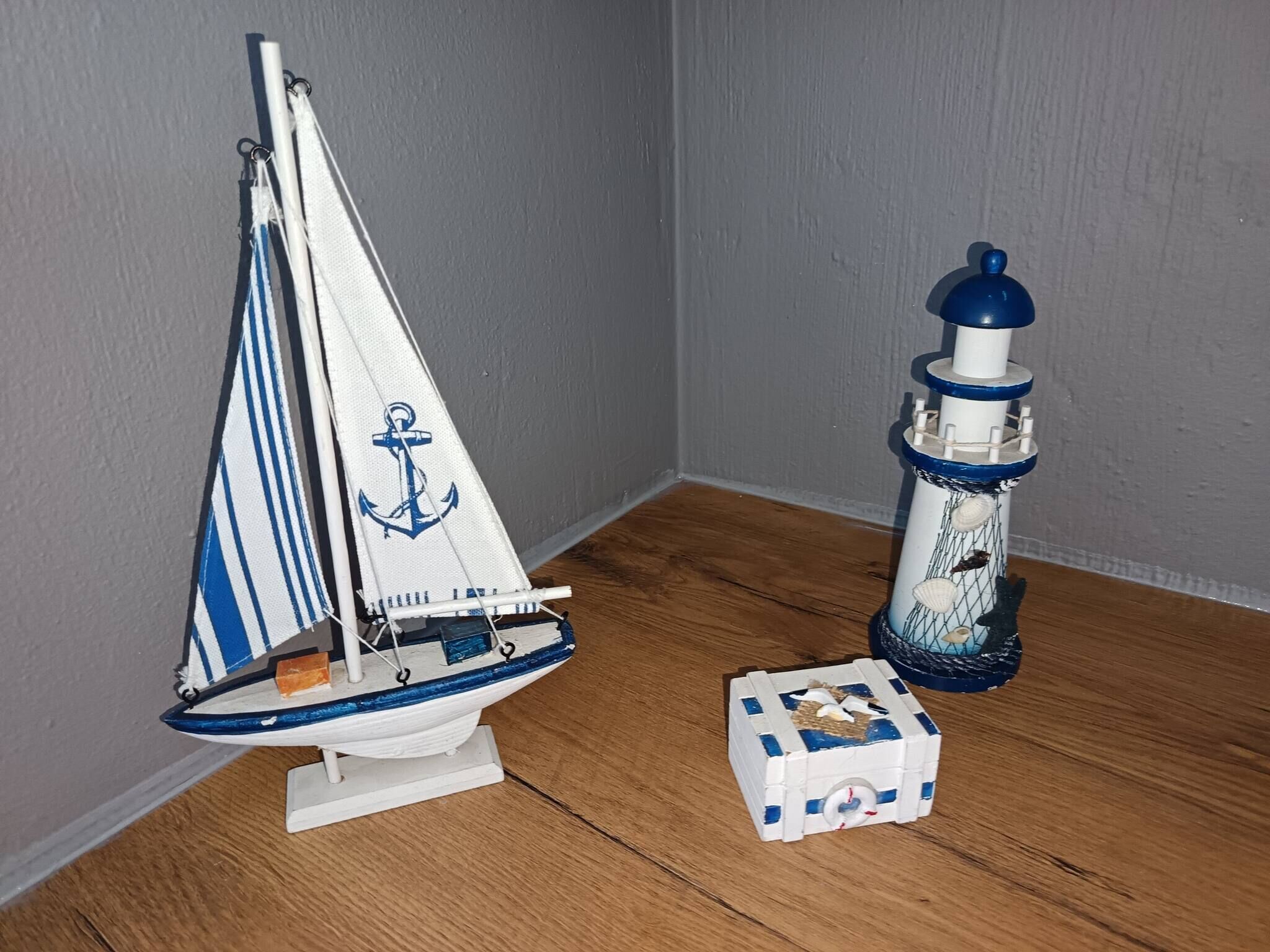 A model sailboat and a lighthouse on a wooden floor.