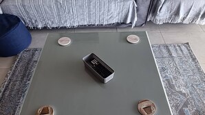 A square table with a remote control in the center, surrounded by four round objects with text. - Luxurious 3-bedroom Apartment With Sea Views in Ramsgate (Margate)