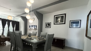 A dining area with a rectangular table, grey chairs, and a chandelier. - Luxurious 3-bedroom Apartment With Sea Views in Ramsgate (Margate)