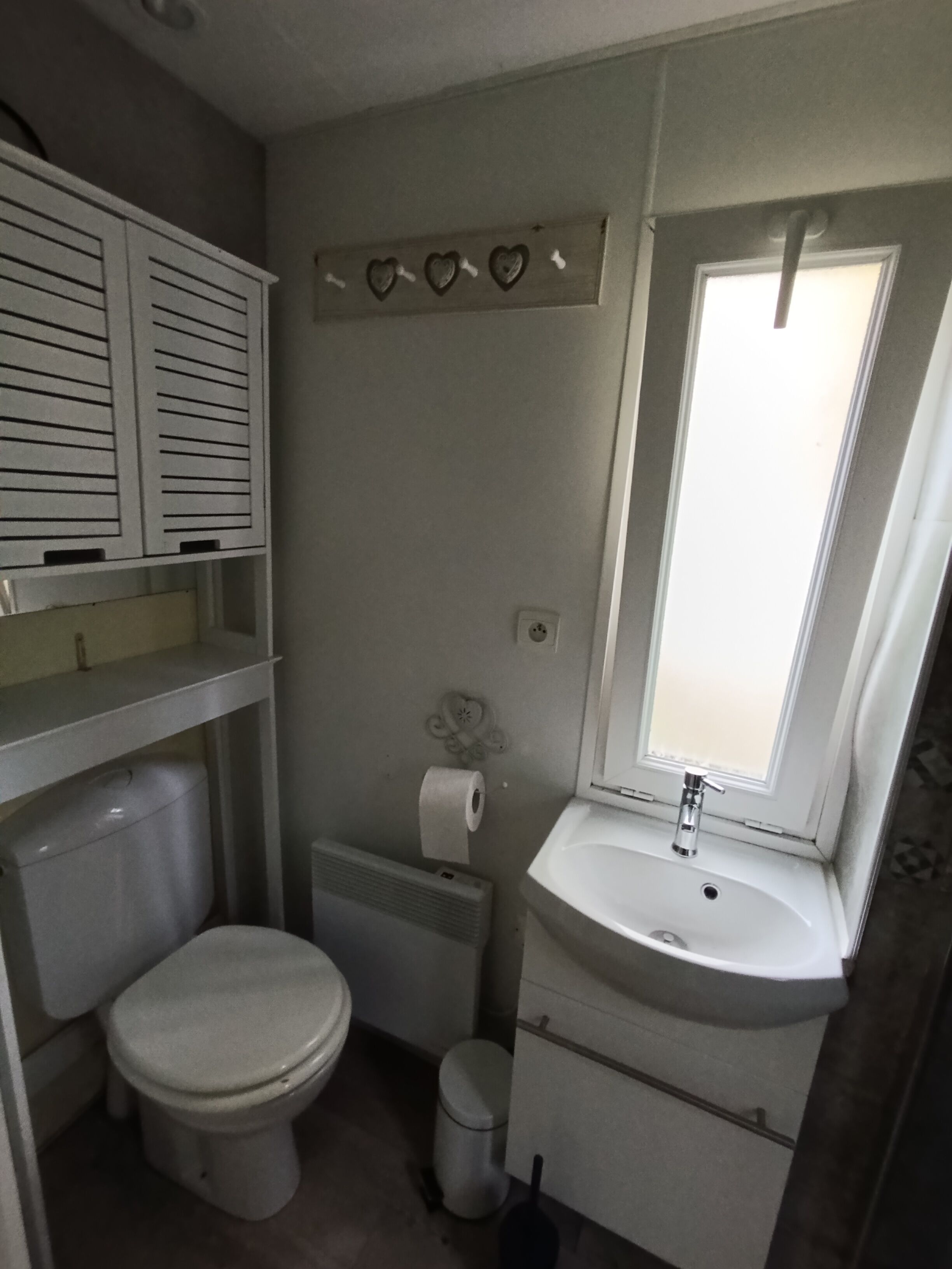 A compact bathroom with a toilet, sink, and a window.