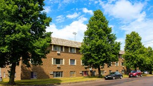 A multi-story brick building with a flat roof, several windows, and a parking lot with cars. - St. Paul Cozy Home Stay-Pets Ok, Pool & GYM Access - 79/Night, 1,750/Month (Saint Paul)