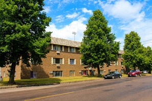 A multi-story brick building with a flat roof, several windows, and a parking lot with cars. - St. Paul Cozy Home Stay-Pets Ok, Pool & GYM Access - 79/Night, 1,750/Month (Saint Paul)