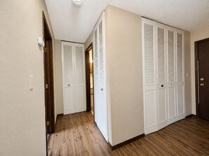 A hallway with a wooden floor, white walls, and a door with louvered closet doors. - St. Paul Cozy Home Stay-Pets Ok, Pool & GYM Access - 79/Night, 1,750/Month (Saint Paul)