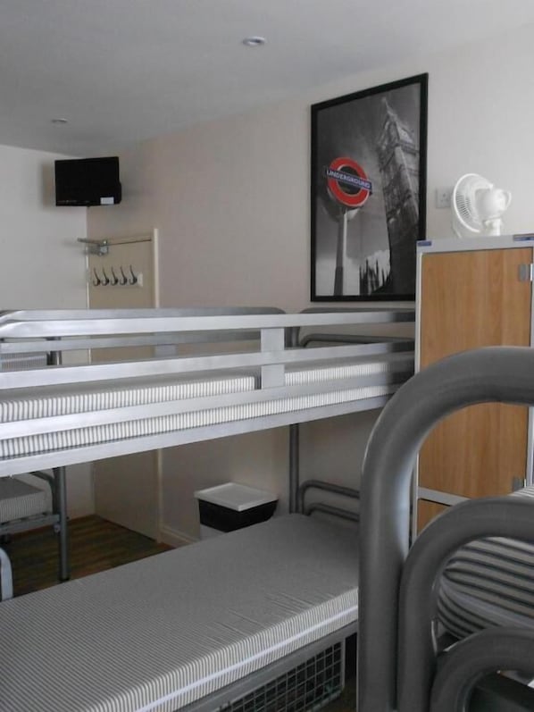 A bunk bed room with a television, a framed picture, and a fan.