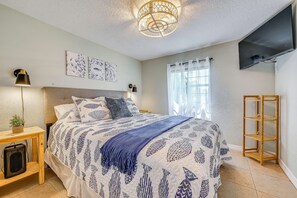 A bedroom with a bed, bedside tables, a television, and artwork on the wall. - Weeki Wachee Springs Gem: Relax and Explore (Spring Hill)