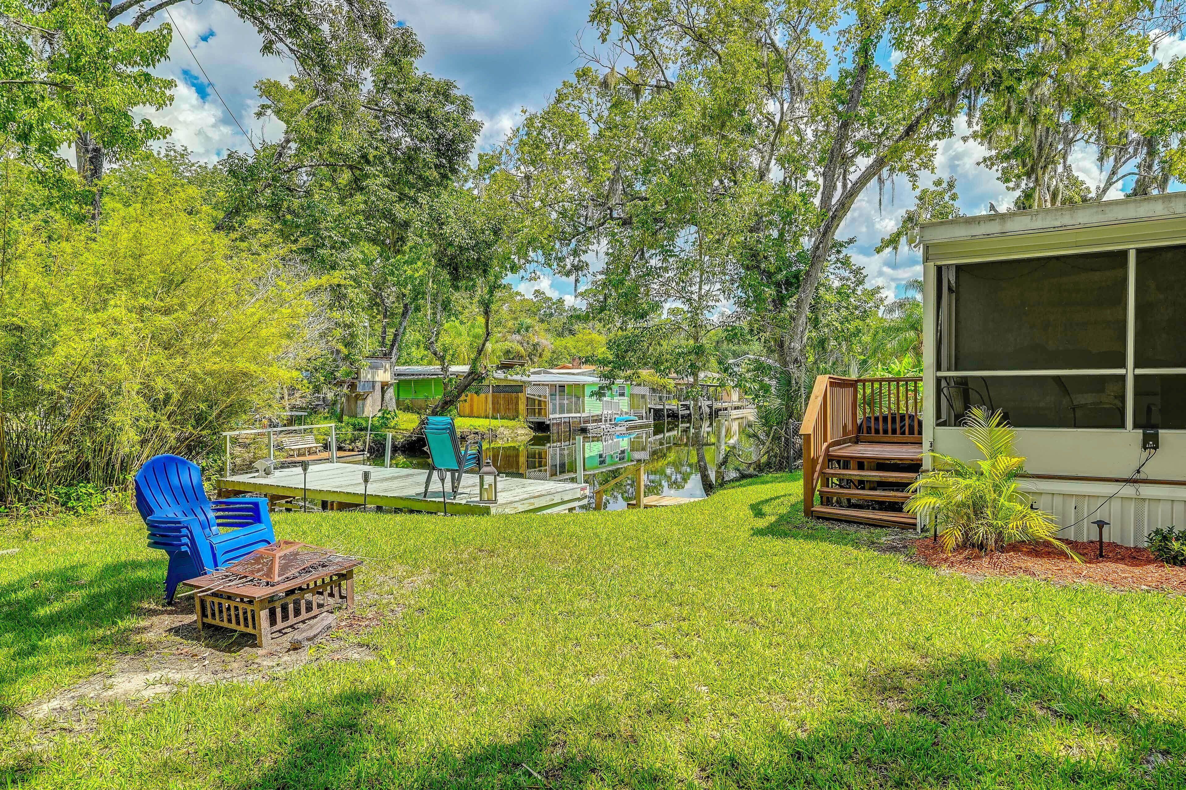 A residential area with a dock, outdoor seating, and a house with a large window.