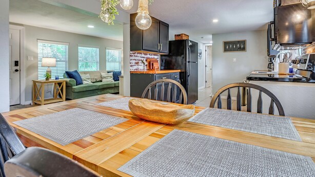 A modern kitchen with a black refrigerator, wooden cabinets, and a hanging light fixture. - Weeki Wachee Springs Gem: Relax and Explore (Spring Hill)