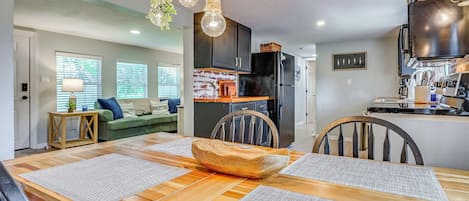 A modern kitchen with a black refrigerator, wooden cabinets, and a hanging light fixture.