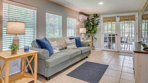 A living room with a grey sofa, a wooden side table, and a large potted plant. - Weeki Wachee Springs Gem: Relax and Explore (Spring Hill)
