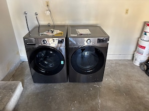 Two front-loading washing machines in a room with a concrete floor and a white wall.