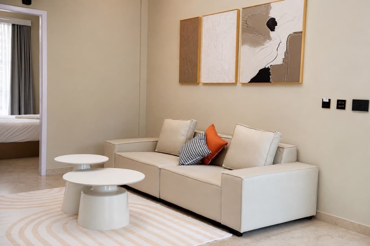A modern living room with a sofa, two side tables, and abstract art on the wall.