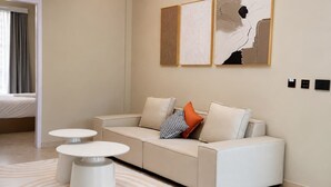 Una sala moderna con un sofá, dos mesas auxiliares y arte abstracto en la pared.