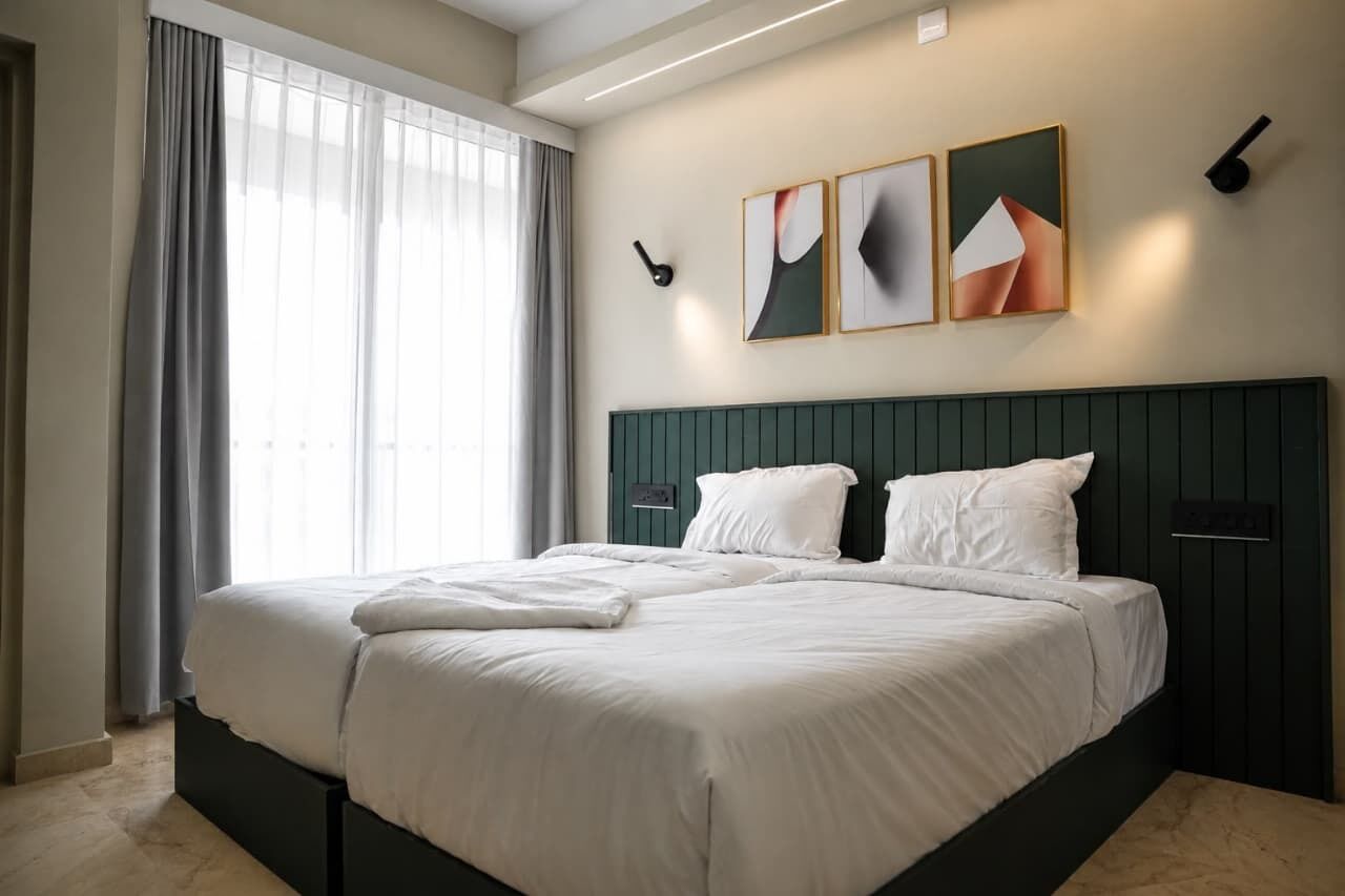 Moderni hotellihuone, jossa on suuri sänky, tumma pääty ja ikkuna, jossa on verhot.