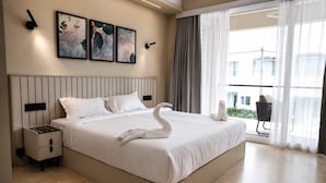Habitación de hotel moderna con una cama grande, una mesita de noche y vistas al exterior.