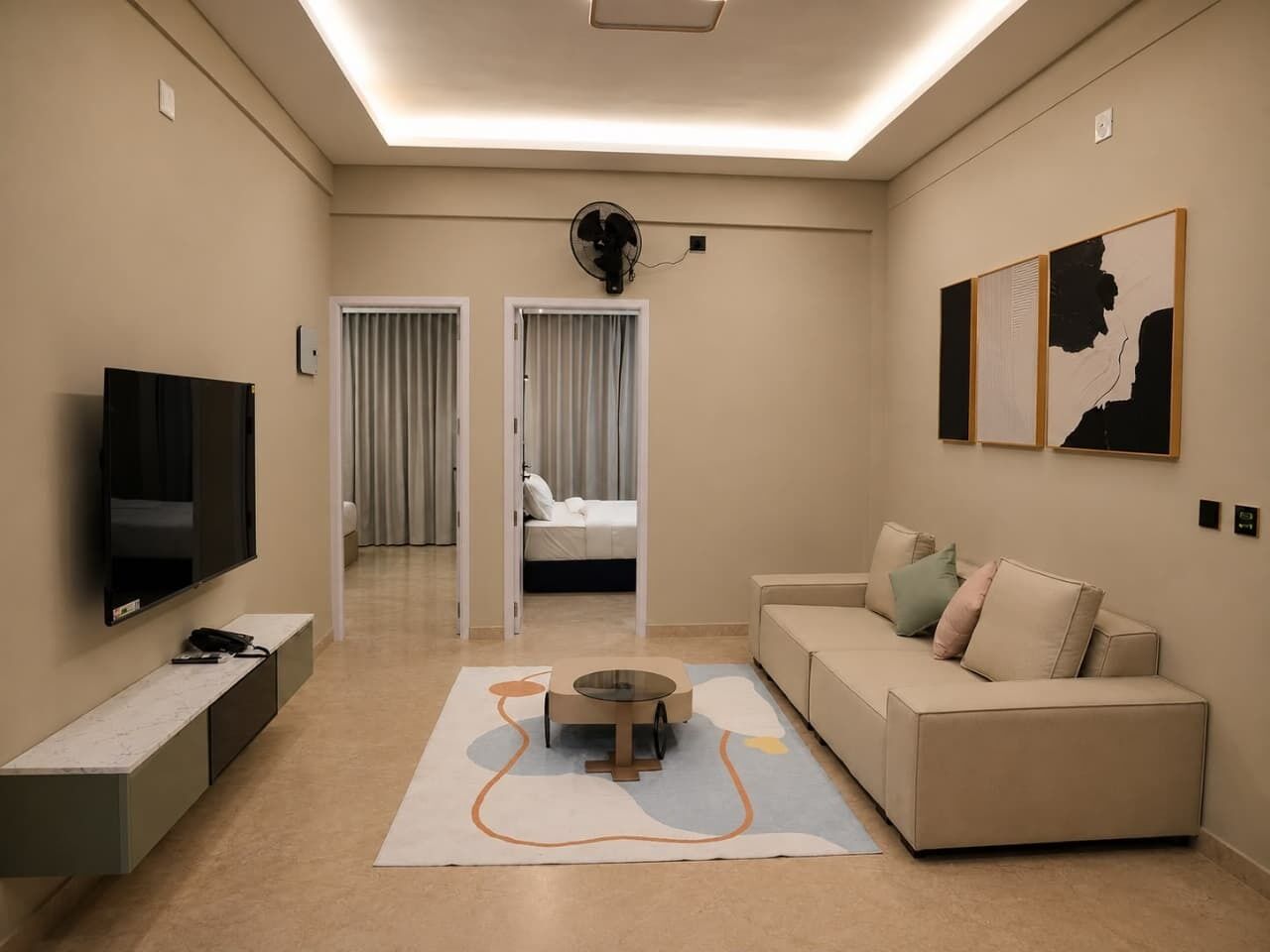 Ein modernes Hotelzimmer mit Flachbildfernseher, einer Couch, einem Couchtisch und Kunstwerken an den Wänden.