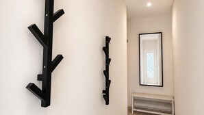 A hallway with a black coat rack, a smaller black wall-mounted rack, and a framed picture on the wall. - The tranquility of the Mediterranean, the comfort of a spacious apartment in Villajoyosa (La Vila Joiosa)