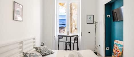 Habitación de hotel con cama, escritorio y silla. Hay una ventana con vistas a un edificio.