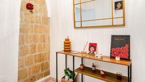 A hallway with a brick wall, a wooden console table with shelves, a mirror, and a hanging light fixture. - NALUSA ROOMS IN CENTRO A TOLEDO (Naples)