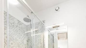 Un bagno con doccia vetrata, un lavandino bianco e uno specchio sopra.