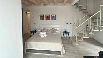 Une chambre à coucher comprenant un lit, un bureau, une chaise, un escalier et une rambarde.