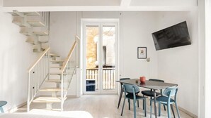 A modern interior with a staircase, a dining area with chairs, and a flat-screen TV mounted on the wall. - NALUSA ROOMS IN CENTRO A TOLEDO (Naples)