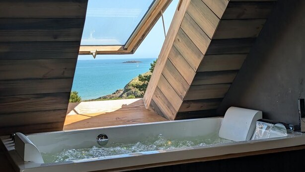 A wooden room with a skylight, a bathtub, and a view of the sea. - The Lomy Shelter. Jacuzzi with ocean view · Movie theater · Pool table (Pléneuf-Val-André)