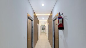 A corridor with doors on both sides, a fire extinguisher mounted on the wall, and a ceiling light. - Collection O Taj Viewpoint Agra (Agra)
