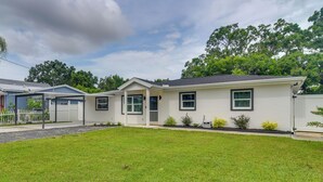 Ein eingeschossiges Haus mit Veranda, Garage und gepflegtem Rasen.