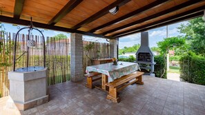 Eine Terrasse im Freien mit einem Holztisch, einer Steinfontäne und einem Grill.