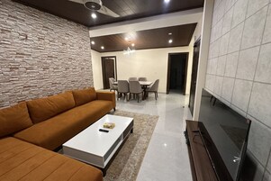 Una sala moderna con sofá, mesa de centro, televisor y comedor.