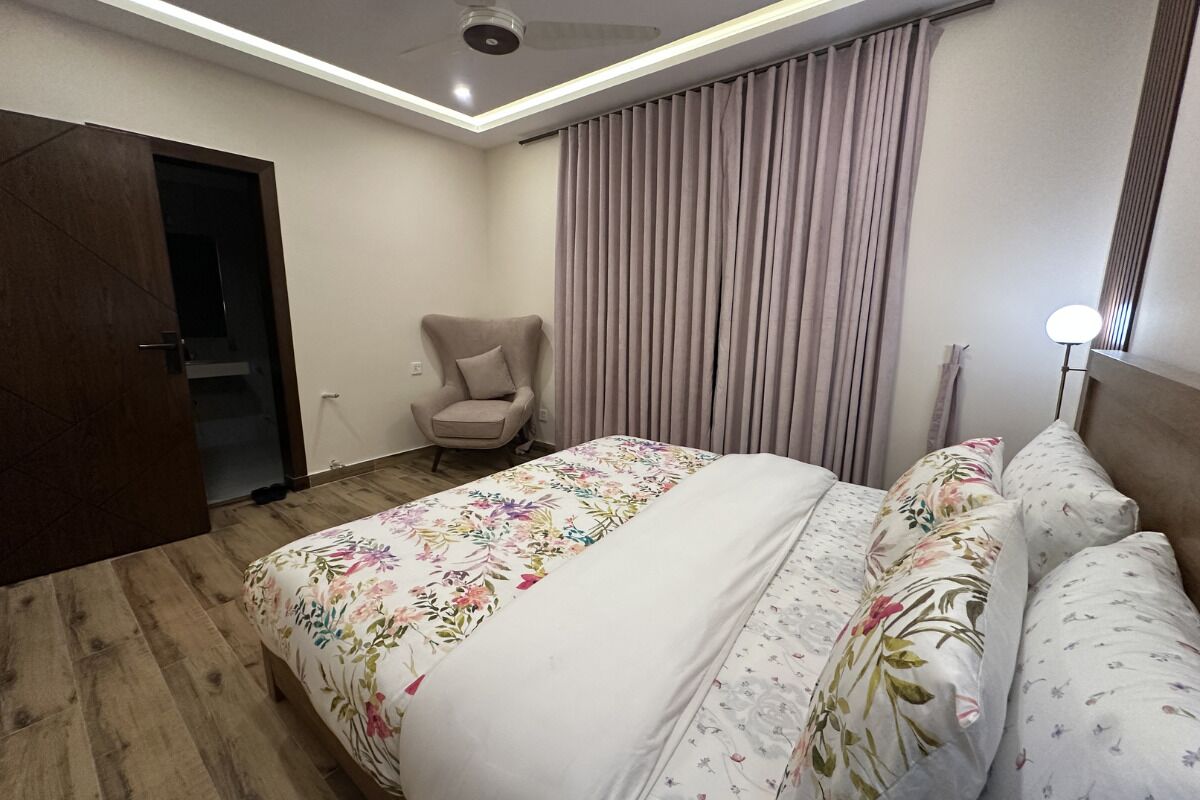 Ein Hotelzimmer mit einem Bett, einem Sessel, einem Vorhang und einer Deckenleuchte.