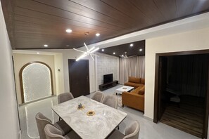 Una sala de estar moderna con comedor, televisor y sofá.