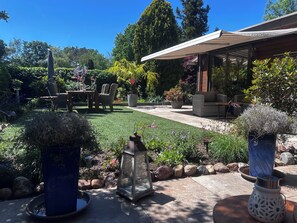 A patio area with outdoor furniture, a covered seating area, and a well-maintained garden with various plants and a lawn.
